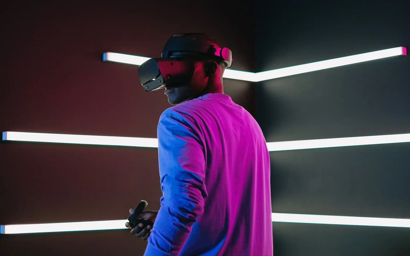 Adult wearing a VR headset in a neon-lit gaming room