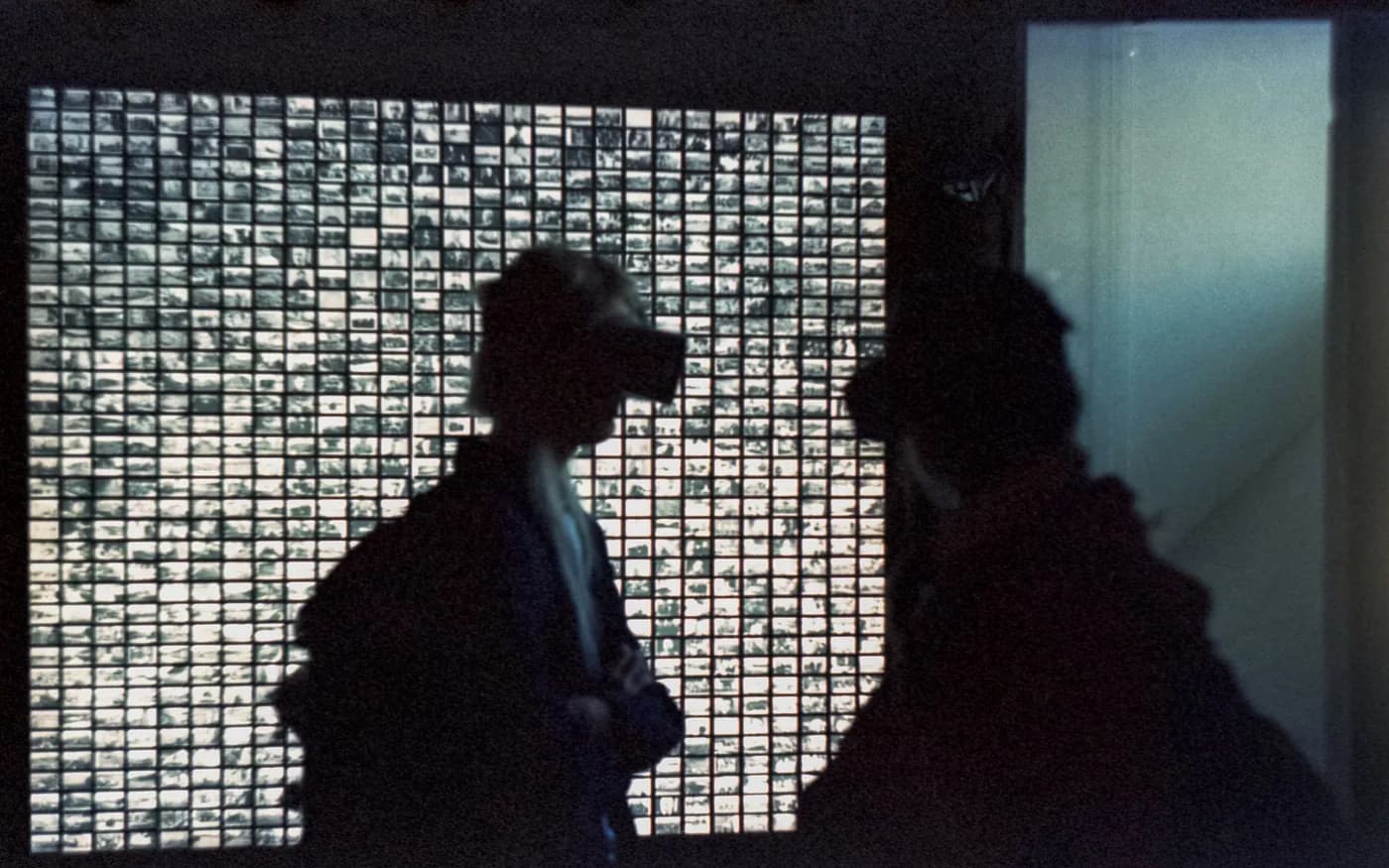 Two adults using virtual reality headsets in front of a digital display